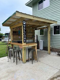 an outdoor bar with stools under it and the words welcome home written on top