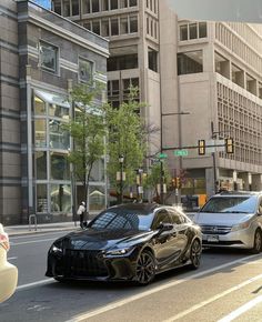 two cars are parked on the street in front of some tall buildings and people walking down the sidewalk