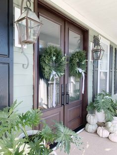 the front door is decorated with wreaths and potted plants for fall decorating