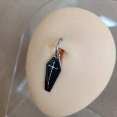 a small black stone with a cross hanging from it's side on a white surface