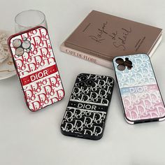 three cell phones sitting on top of a table next to a book and glass cup