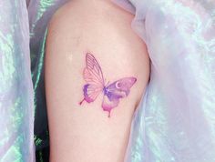 a pink butterfly tattoo on the left thigh and right leg with purple watercolors