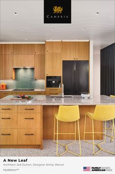 a kitchen with two yellow chairs next to a counter top and an island in the middle