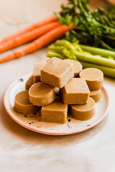 several pieces of tofu on a plate next to carrots and celery