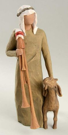 a clay figurine holding a wooden stick and standing next to a goat