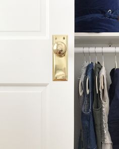 an open closet door with clothes hanging on hooks and pants in the bottom shelf next to it