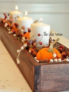 some candles are sitting in a wooden box with berries and pumpkins on the table