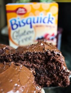 there is a piece of chocolate cake with frosting on the plate and a package of biscuits in the background