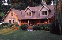 a large house sitting in the middle of a lush green field next to a forest