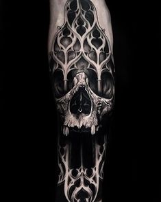 a man's leg with a black and white tattoo design on it, featuring a skull