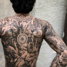 the back of a man's body with tattoos on it and an angel surrounded by demons