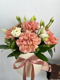 a bouquet of pink and white flowers in a vase with a ribbon tied around it