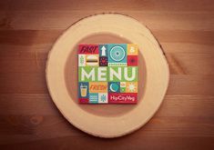 a piece of wood with the word menu written in colorful blocks on it, sitting on top of a wooden table