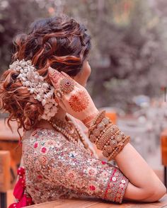 a woman with henna on her head and hands behind her ear looking at something