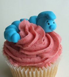 there is a cupcake with pink frosting and two blue teddy bears on top