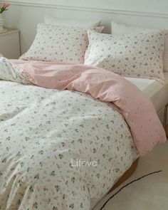 a bed with pink and white comforters in a bedroom next to a plant on the floor