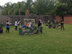 some kids are playing in the back yard with their own camouflaged couch and chair