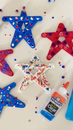 red, white and blue stars are sitting on the table next to some glue bottles