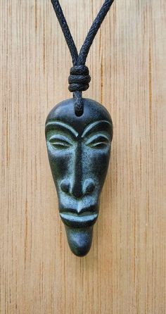 Face pendant, tiny face necklace. Hand-carved from natural stone called green granite by myself. The colour of the stone is dark green almost looks black. This is Protection and goodluck talismen in south Indian tradition. The size of the pendant is approxmatly 3.5cm x 1.5cm  (1.3 x 0.5inches). The pendant comes with an adjustable black waxed cotton cord. Not only are these pendants a beautiful thing to wear as part of your jewellery collection, but they are also very pleasing to the touch. The Green Granite, Talisman Jewelry, Face Pendant, Hand Carved Stone, Face Necklace, Mask Necklace, Personalized Pendant, Looks Black, Bone Carving