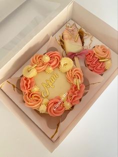 two cupcakes in a box with the word mom written on them and pink icing