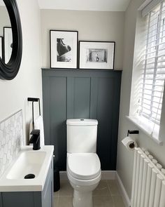 a white toilet sitting in a bathroom next to a sink and radiator with pictures on the wall