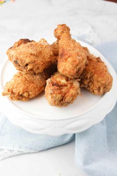 some fried food on a white plate with a blue napkin and flowers in the background