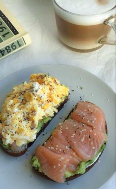 a plate topped with two pieces of bread covered in toppings next to a cup of coffee