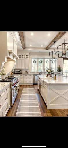 a large kitchen with white cabinets and wood flooring, along with an area rug in the middle