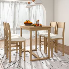 a dining room table with chairs and a bowl of fruit on the table next to it