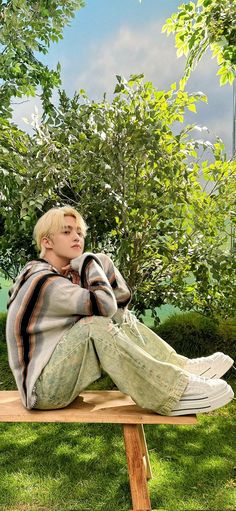 a young man sitting on top of a wooden bench