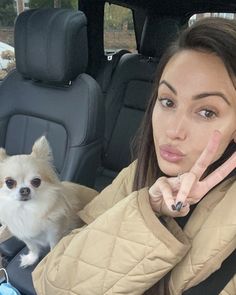 a woman sitting in the back seat of a car with her dog