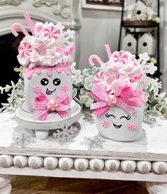 two decorated cups sitting on top of a table next to each other with pink bows