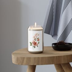 a candle sitting on top of a wooden table next to a black bowl and towel