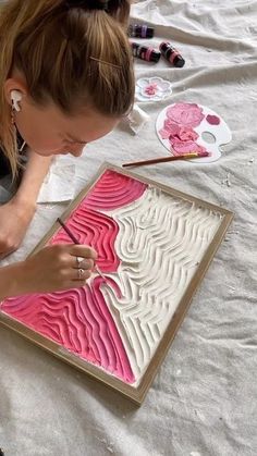 a woman is working on an art project with pink and white paper in front of her