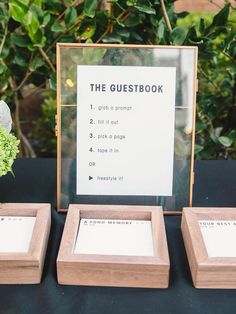 the guest book is set up on a table next to two small wooden frames with flowers in them