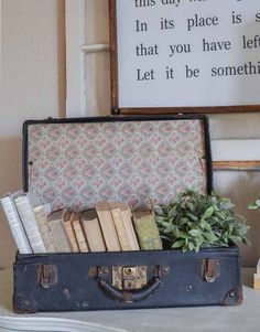 an old suitcase filled with books on top of a table next to a potted plant