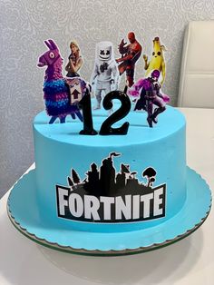 a blue cake with toy figures on it and the number 12 is for fortnite