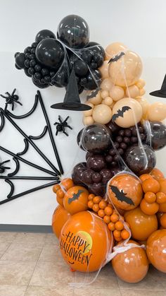 halloween balloons and decorations are arranged on the floor in front of a wall with bats