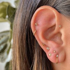 a close up of a person wearing ear piercings with gold colored beads and stars on them