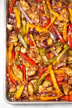 a pan filled with chicken, peppers and onions