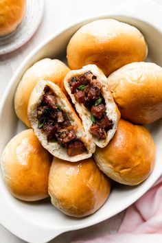 a white bowl filled with rolls covered in meat