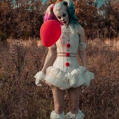 a woman dressed as a clown holding a red balloon