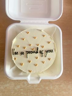 a cake in a plastic container with the words i'm so proud of you written on it