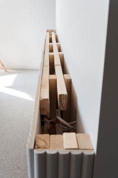 an open drawer in the corner of a room filled with wooden pieces and wires, next to a radiator