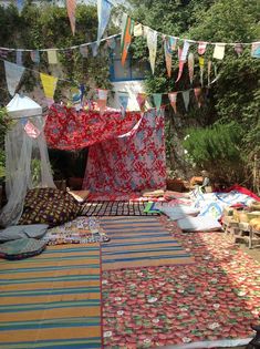 a bed covered in lots of blankets and pillows next to some tables with food on them