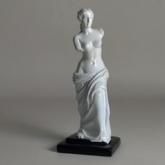 a white statue is standing on a black base and it looks like she's pregnant