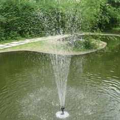 a fountain spewing water into a pond surrounded by greenery