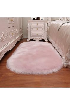 a white bed with a pink rug on top of it next to a wooden floor