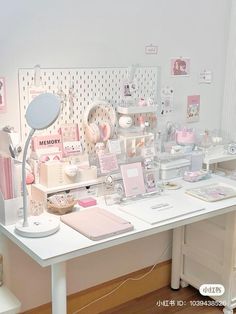 a white desk topped with lots of pink and white items next to a wall mounted clock