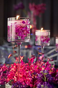 purple flowers and candles are in glass vases